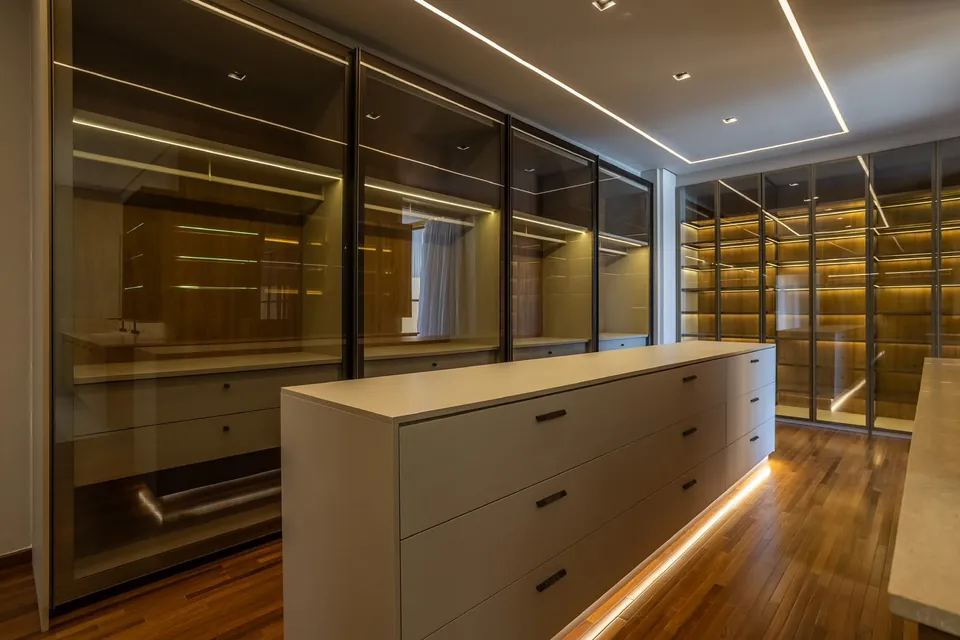 Closet com armários de vidro e iluminação embutida